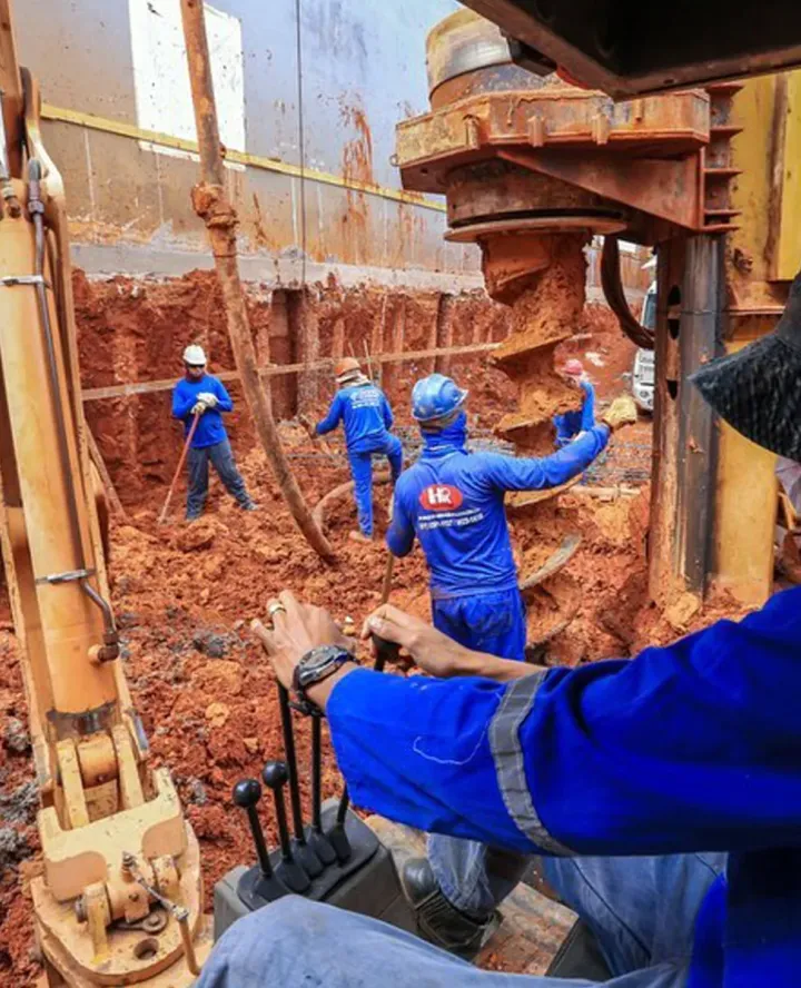 Trado escavando estaca em obra da HR Fundações em Brasília, com equipe posicionando a armadura